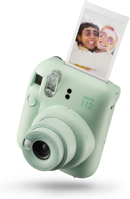 Fujifilm Instax Mini 12 instant camera in sage green with printed photo ejecting from top