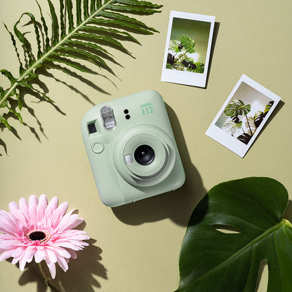 Instax Mini 12 camera held in hand showing compact, lightweight design