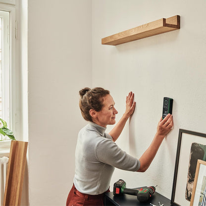 Person using Bosch Truvo detector to scan a wall before drilling