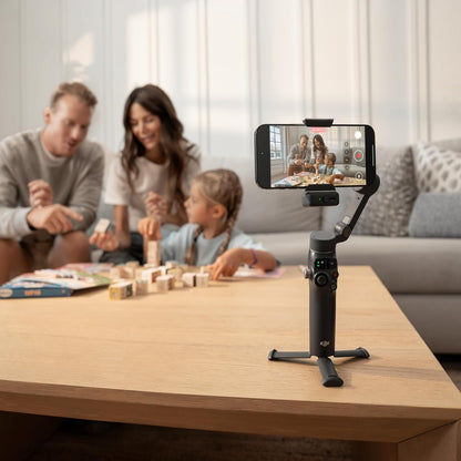 Family playing a board game with a smartphone on a gimbal in the foreground